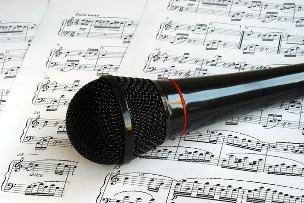 Un micrófono negro en las hojas de música —  Fotos de Stock