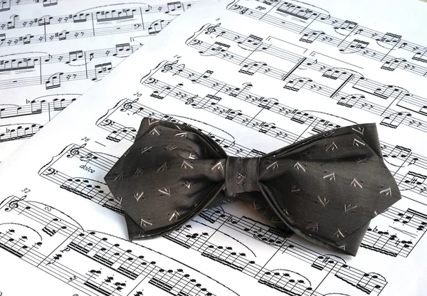 A gray bow tie on the top of music sheet — Stock Photo, Image