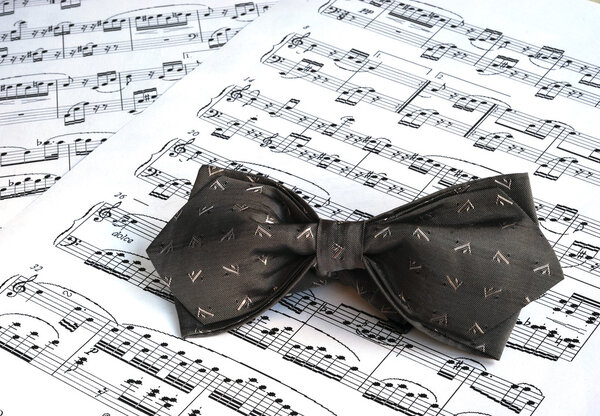 A gray bow tie on the top of music sheet