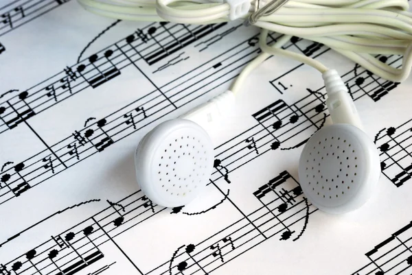 An ear phone on the top of a music sheet — Stock Photo, Image