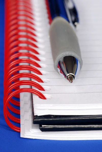 Una penna e un quaderno con raccoglitore rosso — Foto Stock