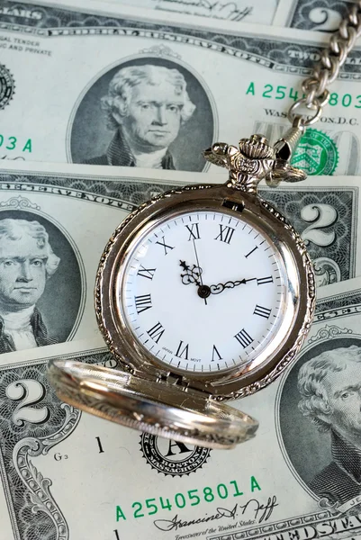 Reloj de bolsillo viejo en una pila de billetes de $2 Imagen de stock