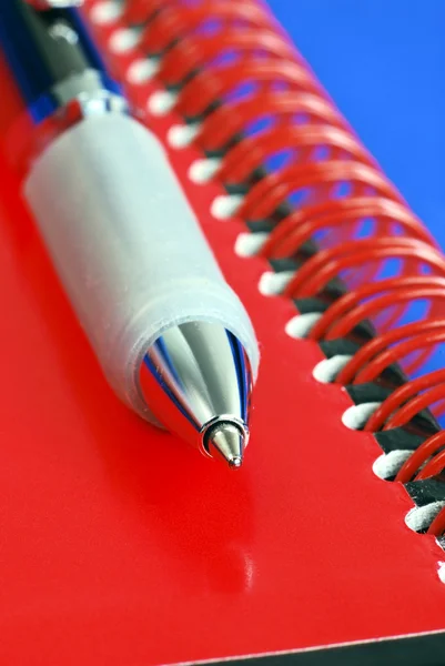 Una penna sulla parte superiore di un taccuino rosso — Foto Stock