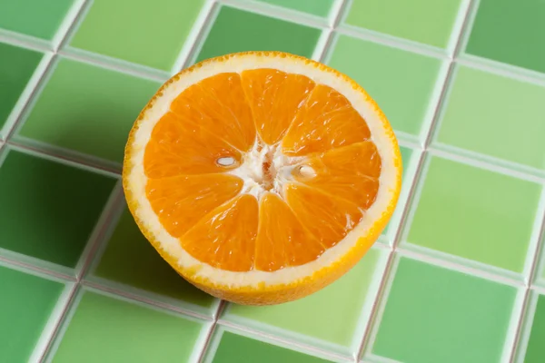 De helft van de sappige oranje op groene balk — Stockfoto