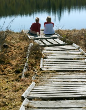 Two girls sit on pier clipart