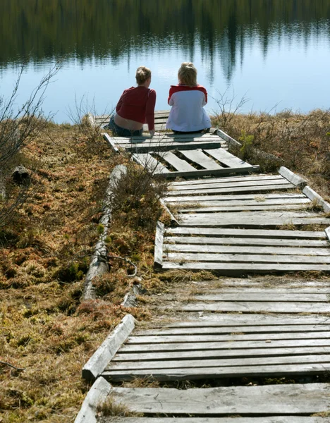 Zwei Mädchen sitzen auf Seebrücke — Stockfoto