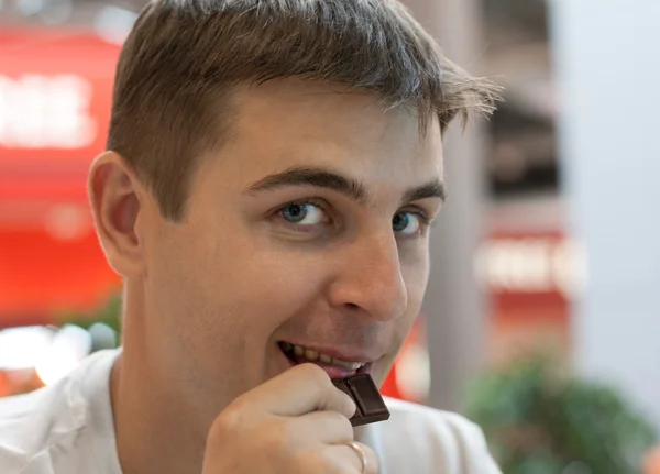 Young man eats chocolate — Stock Photo, Image