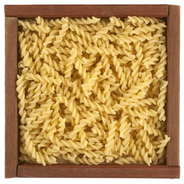 Uncooked fusilli pasta in wooden box clipart