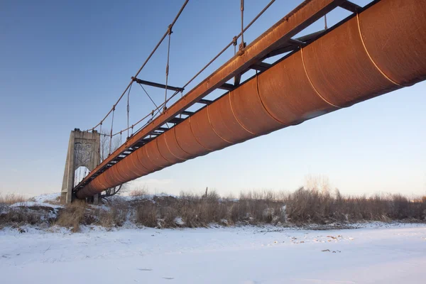 Roestige meetgoot opgehangen boven een rivier — Stockfoto