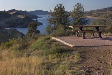 Table on shore of mountain reservoir clipart