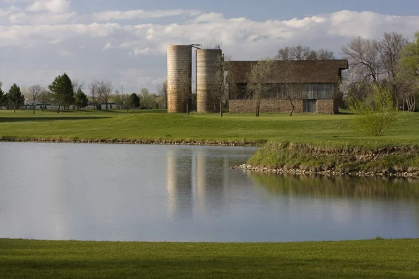 Schuur met twee silo's omgeven door weiden — Stockfoto