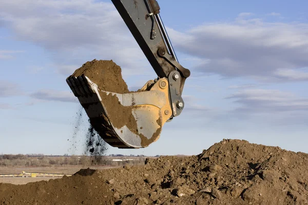 Excavator arm and scoop digging dirt — Stock Photo, Image