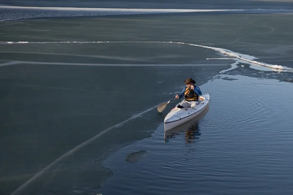 Гребля каноэ на покрытом льдом озере — стоковое фото