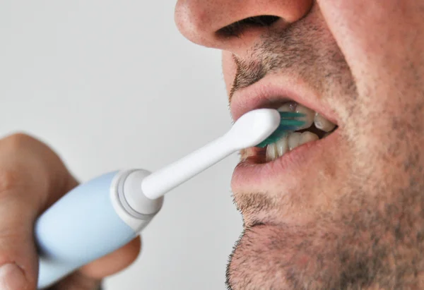 Человек чистит зубы электрическим — стоковое фото