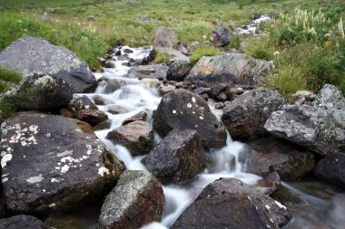 Stream of mountain river among stones clipart