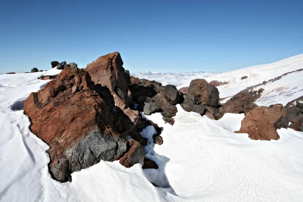 Pedras na neve contra um céu azul claro — Fotografia de Stock