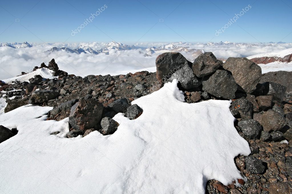 Stones in snow against clear blue sky and mountains in Caucasus