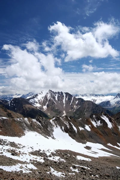 Skały, śnieg, chmury i niebo w górach Kaukazu — Zdjęcie stockowe