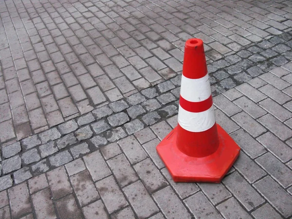 Um cone de trânsito numa estrada de paralelepípedos — Fotografia de Stock