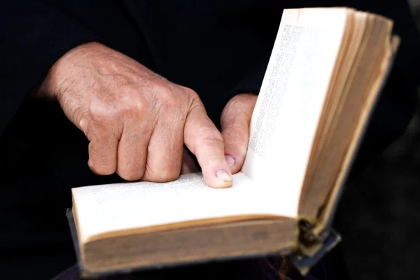 Старшие руки на старой книге — стоковое фото