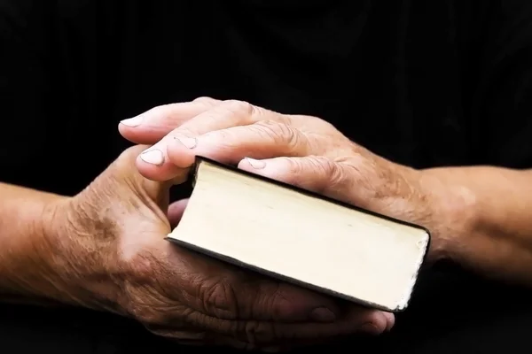 Старшие руки на старой книге — стоковое фото