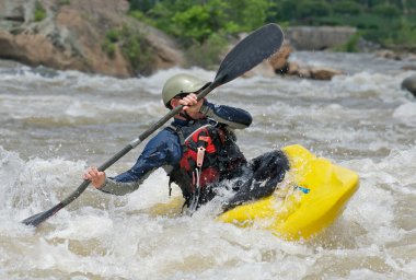 Kayaker fighting the rapids of a river. clipart