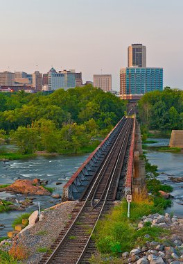 Cityscape of train tracks over a river. clipart