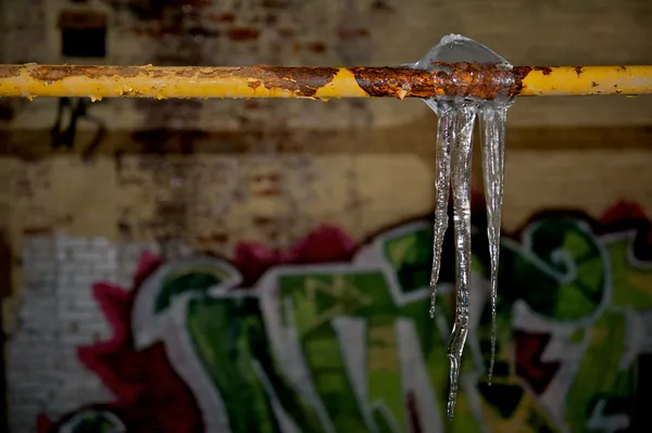Eiszapfen hängen an einem Rohr — Stockfoto