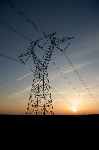 Linhas de energia silhuetas por um pôr do sol . — Fotografia de Stock