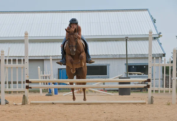 Atletische tiener meisje springen van een paard — Stockfoto