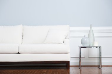 White Sofa and Glass End Table Against Blue Wall clipart