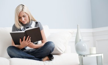 Woman Sitting on Couch and Reading a Book clipart