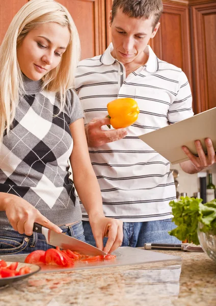 Young Man Holding Book Next to Woman Cutting Tom — Stock Photo, Image