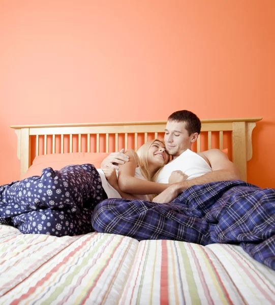 Νεαρό ζευγάρι στην πιτζάμες κάθεται στο κρεβάτι — Φωτογραφία Αρχείου