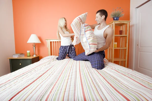 Jeune couple agenouillé sur le lit ayant un oreiller Figue — Photo