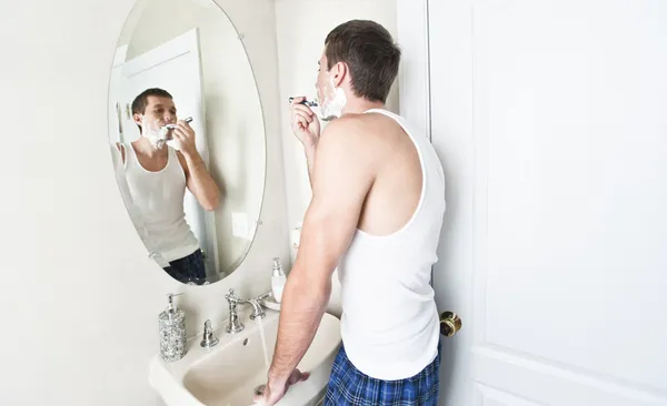 Hombre joven en el baño de afeitar —  Fotos de Stock