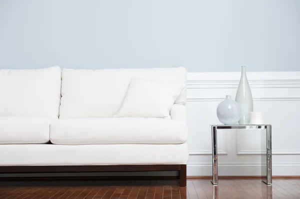 Sofá branco e mesa de extremidade de vidro contra parede azul — Fotografia de Stock