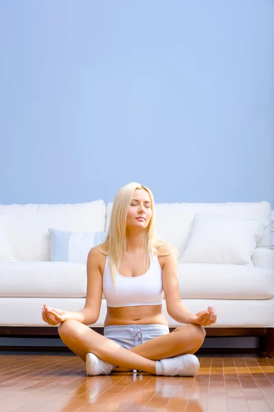 Jonge vrouw zittend op de houten vloer mediteren — Stockfoto