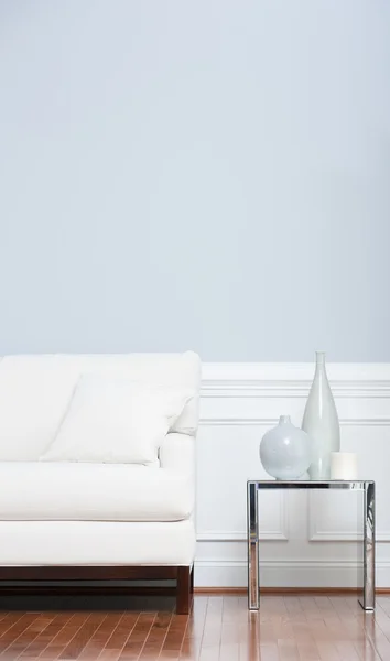 Sofá branco e mesa de extremidade de vidro contra parede azul — Fotografia de Stock