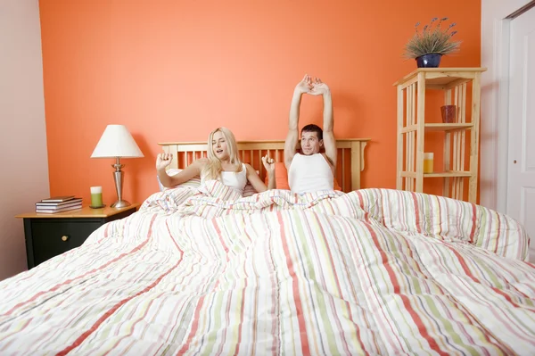 Fiatal pár az ágy nyújtás fekve — Stock Fotó