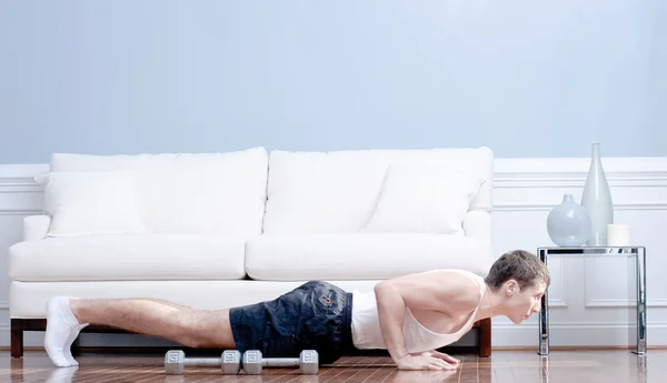 Homem fazendo flexões na sala de estar — Fotografia de Stock