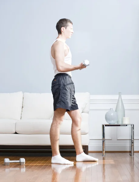 Mann mit Armgewichten im Wohnzimmer — Stockfoto