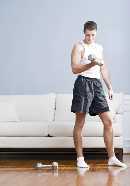 Hombre usando pesos de brazo en la sala de estar — Foto de Stock