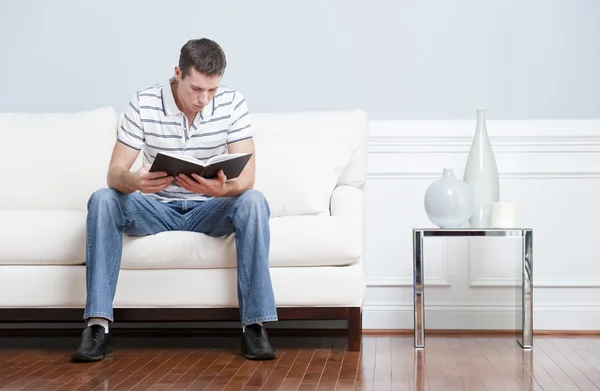 リビング ルームのソファの上を読んでいる人 — ストック写真