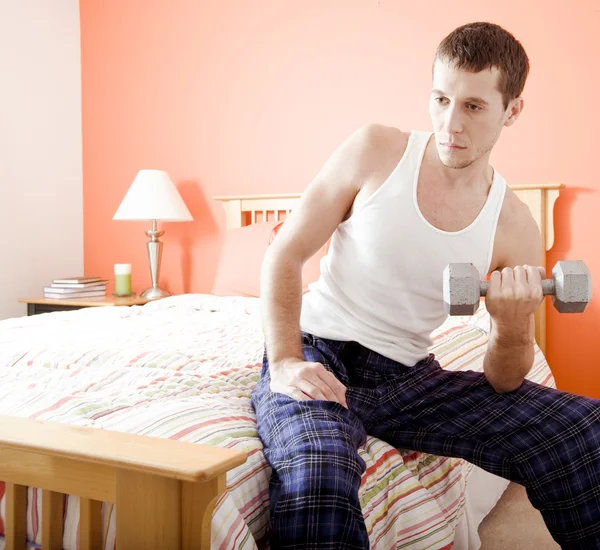Uomo che utilizza il peso del braccio in camera da letto — Foto Stock