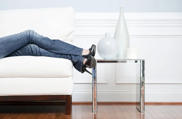 Gambe da donna reclinabili sul divano bianco — Foto Stock