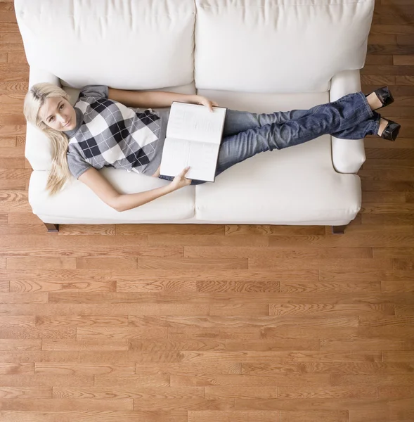 Pohled ženy s knihou na gauči — Stock fotografie