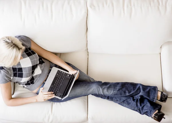 Вид сверху на женщину на диване с ноутбуком — стоковое фото