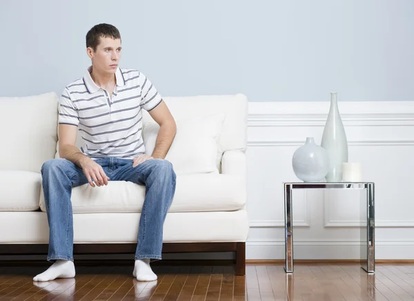 Homem sentado no sofá da sala de estar — Fotografia de Stock