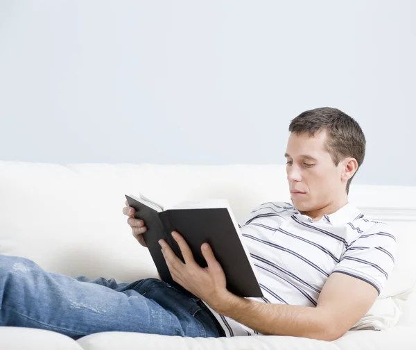 Homem leitura no sofá — Fotografia de Stock